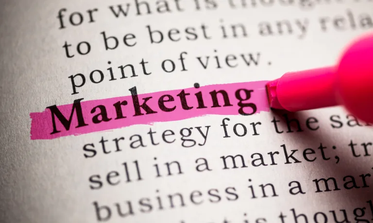 Word 'Marketing' highlighted in pink in a book, symbolising focus on marketing strategy