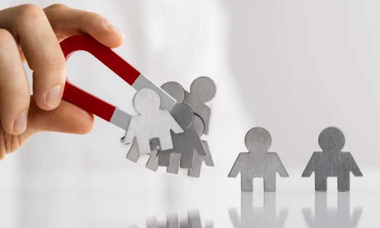 Illustration of a hand holding a magnet, attracting multiple people icons